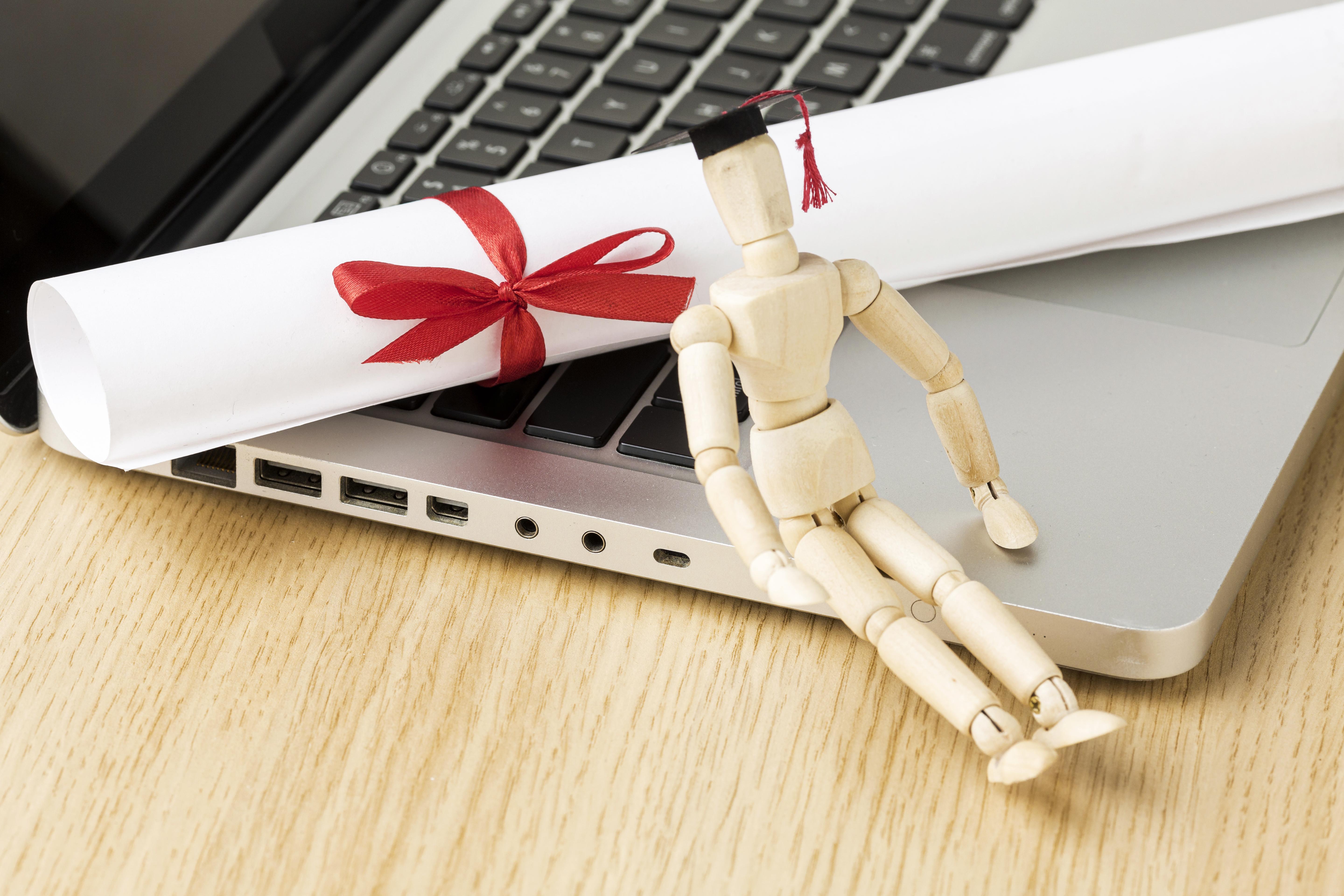 high-angle-laptop-with-wooden-figurine-academic-cap.jpg